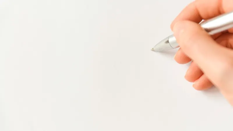 Mano con un bolígrafo sobre una hoja en blanco