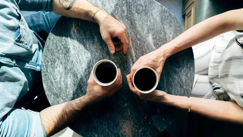 Dos personas conversando con un café